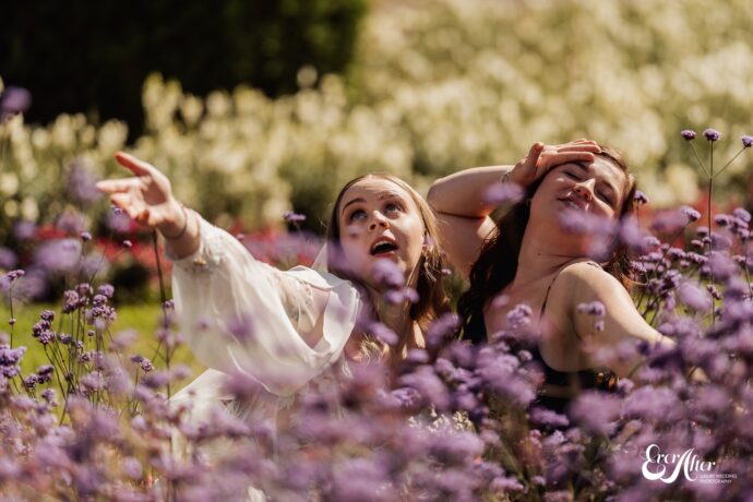 Bride and friend dramatically posing in a bed of flowers
